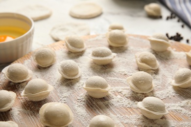 Raw dumplings on wooden board, closeup. Process of cooking