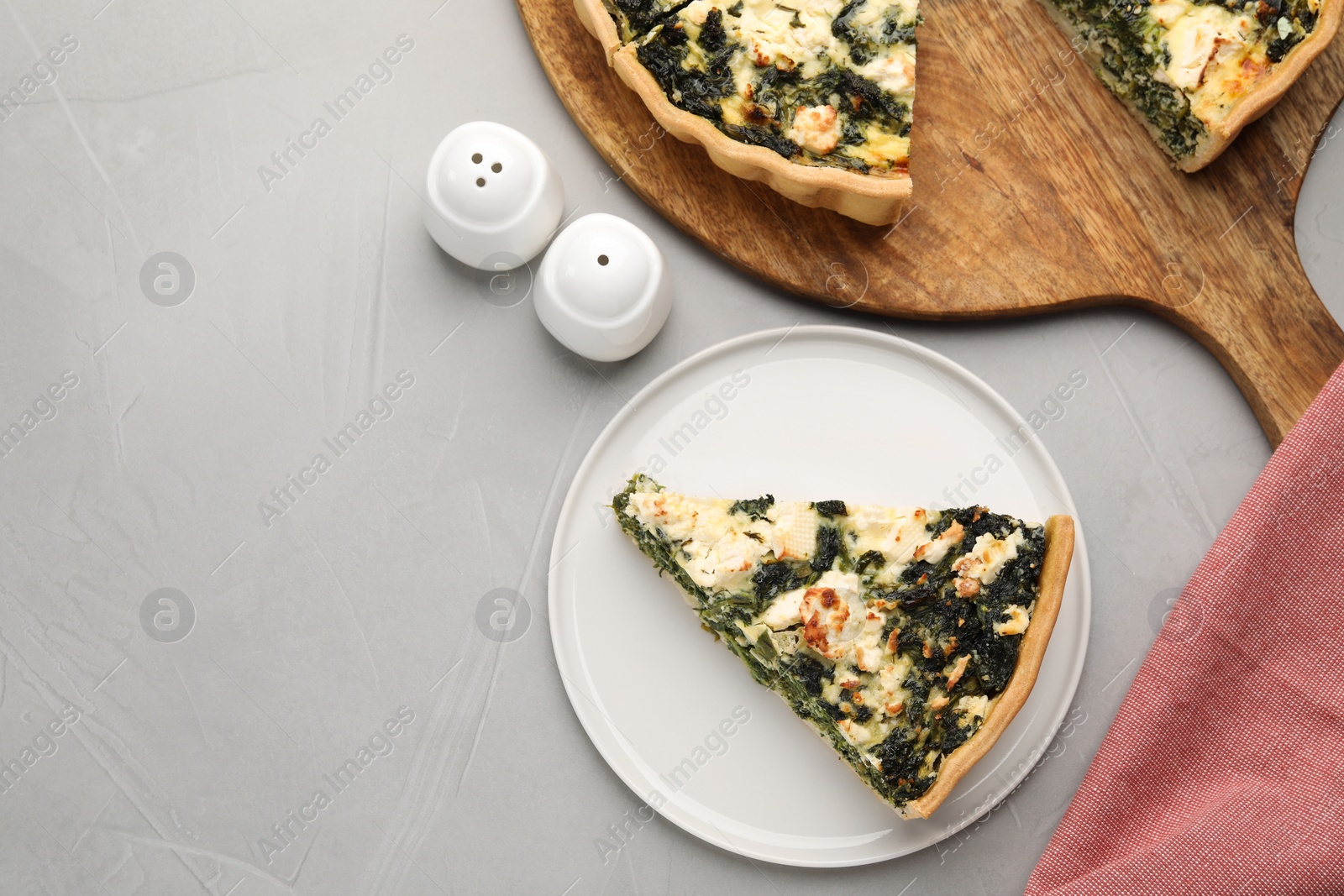 Photo of Delicious homemade spinach quiche on light gray table, flat lay. Space for text