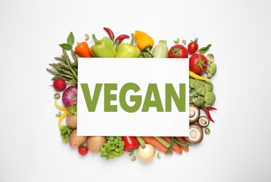 Image of Paper card with word Vegan and fresh vegetables on white background, flat lay