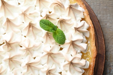 Photo of Delicious lemon meringue pie decorated with mint on wooden table, top view