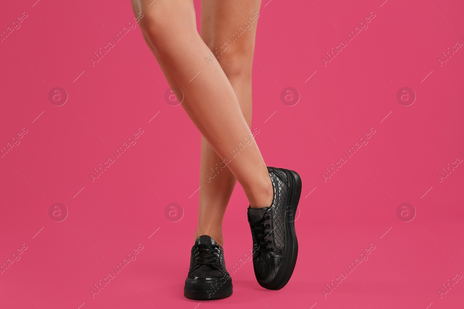 Photo of Woman wearing shoes on pink background, closeup