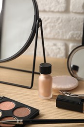 Photo of Mirror and makeup products on wooden dressing table, closeup