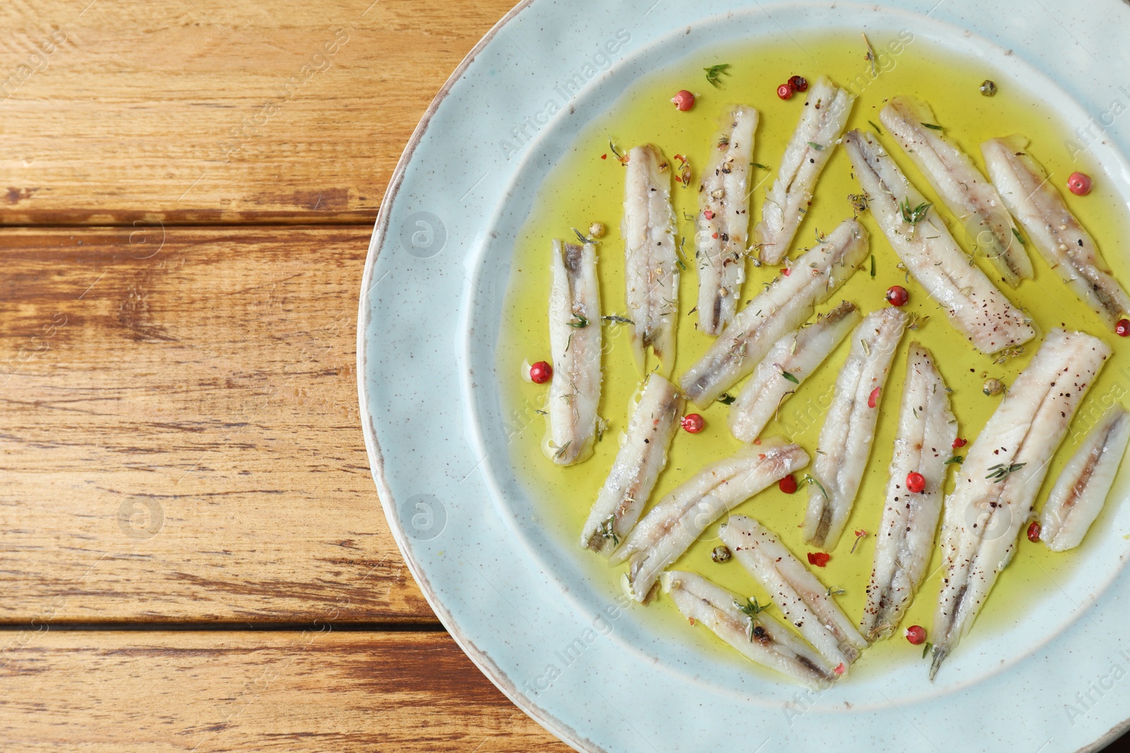 Photo of Tasty pickled anchovies with spices on wooden table, top view. Space for text