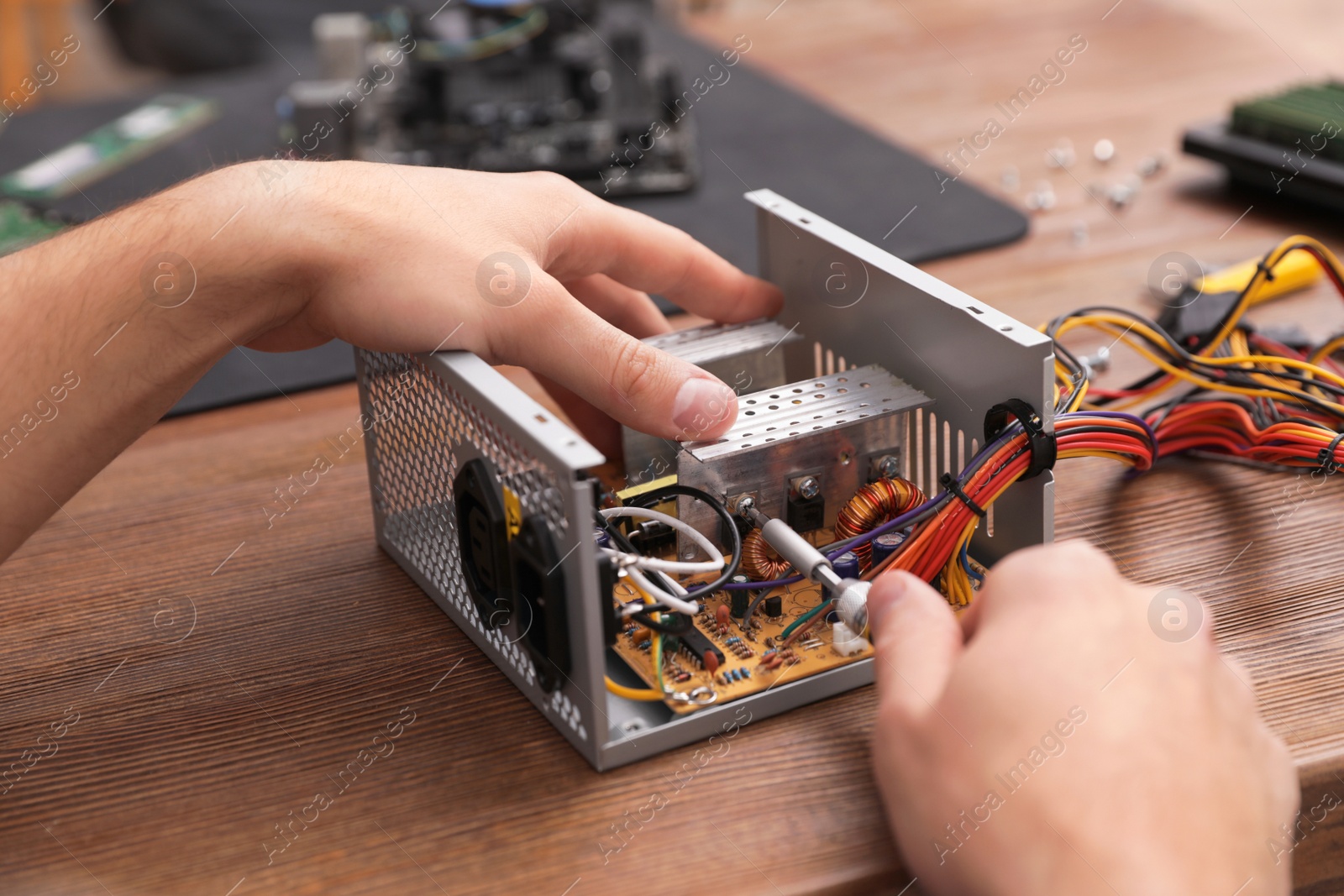 Photo of Male technician repairing power supply unit at table, closeup