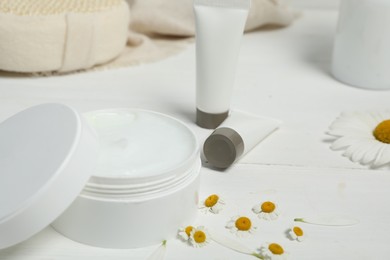 Photo of Cosmetic products and chamomiles on white wooden table