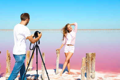 Photo of Professional photographer taking photo of woman near pink lake on sunny day