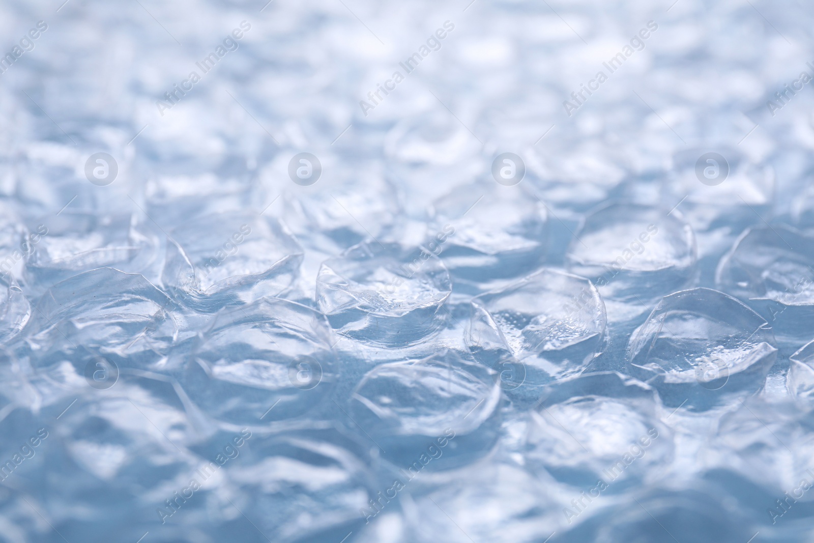 Photo of Transparent bubble wrap on light blue background, closeup