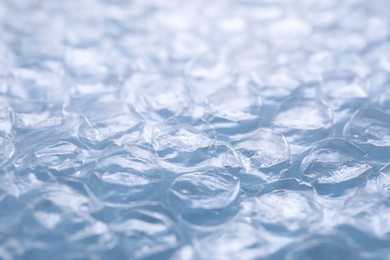 Photo of Transparent bubble wrap on light blue background, closeup