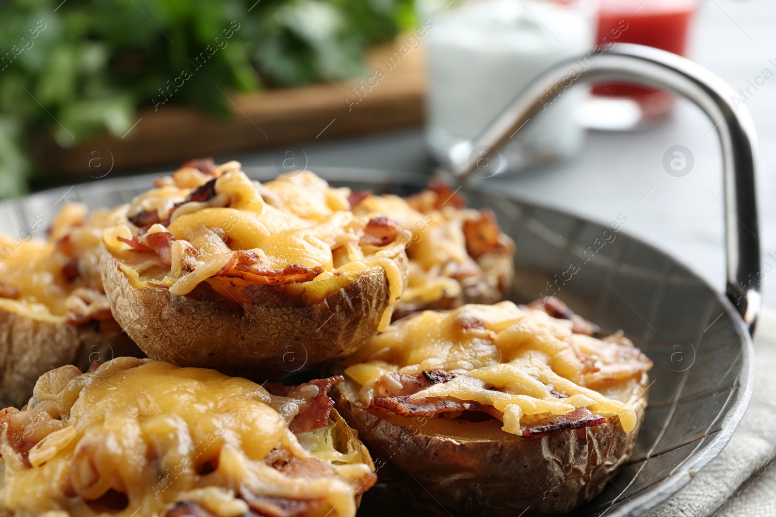 Photo of Frying pan of baked potatoes with cheese and bacon on table, closeup