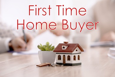 Image of First time home buyer. House model, plant and keys on wooden table, selective focus. Couple signing contract with real estate broker in office, closeup