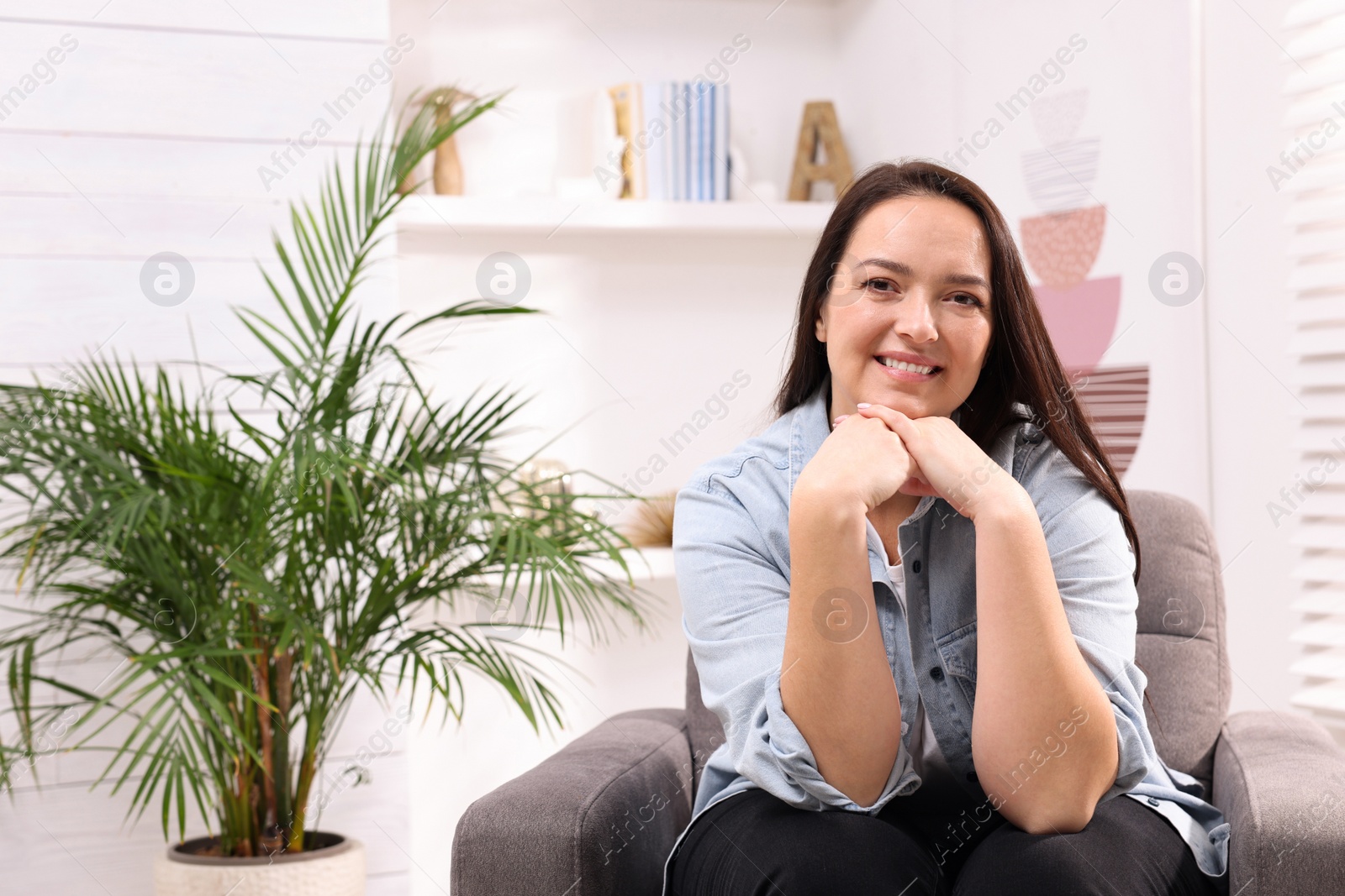 Photo of Beautiful overweight woman sitting in armchair at home