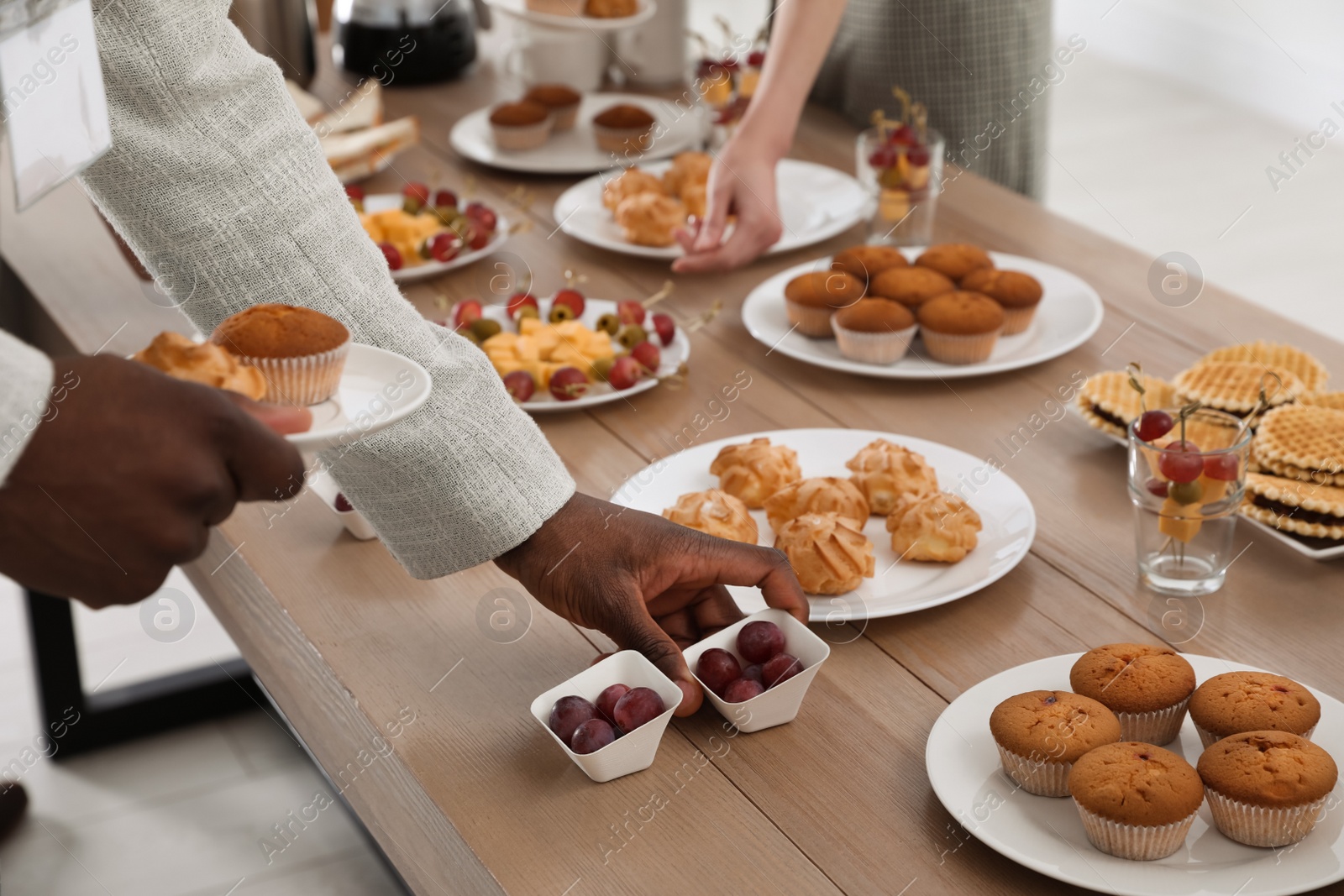 Photo of People near table with different delicious snacks during coffee break, closeup