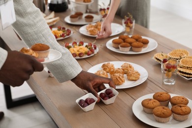 People near table with different delicious snacks during coffee break, closeup