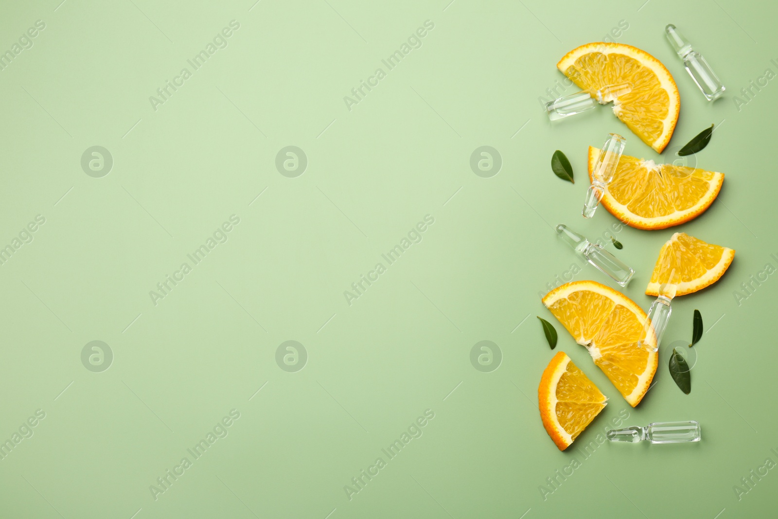 Photo of Skincare ampoules with vitamin C, slices of orange and leaves on light green background, flat lay. Space for text