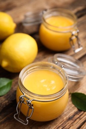 Photo of Delicious lemon curd in glass jar on wooden table