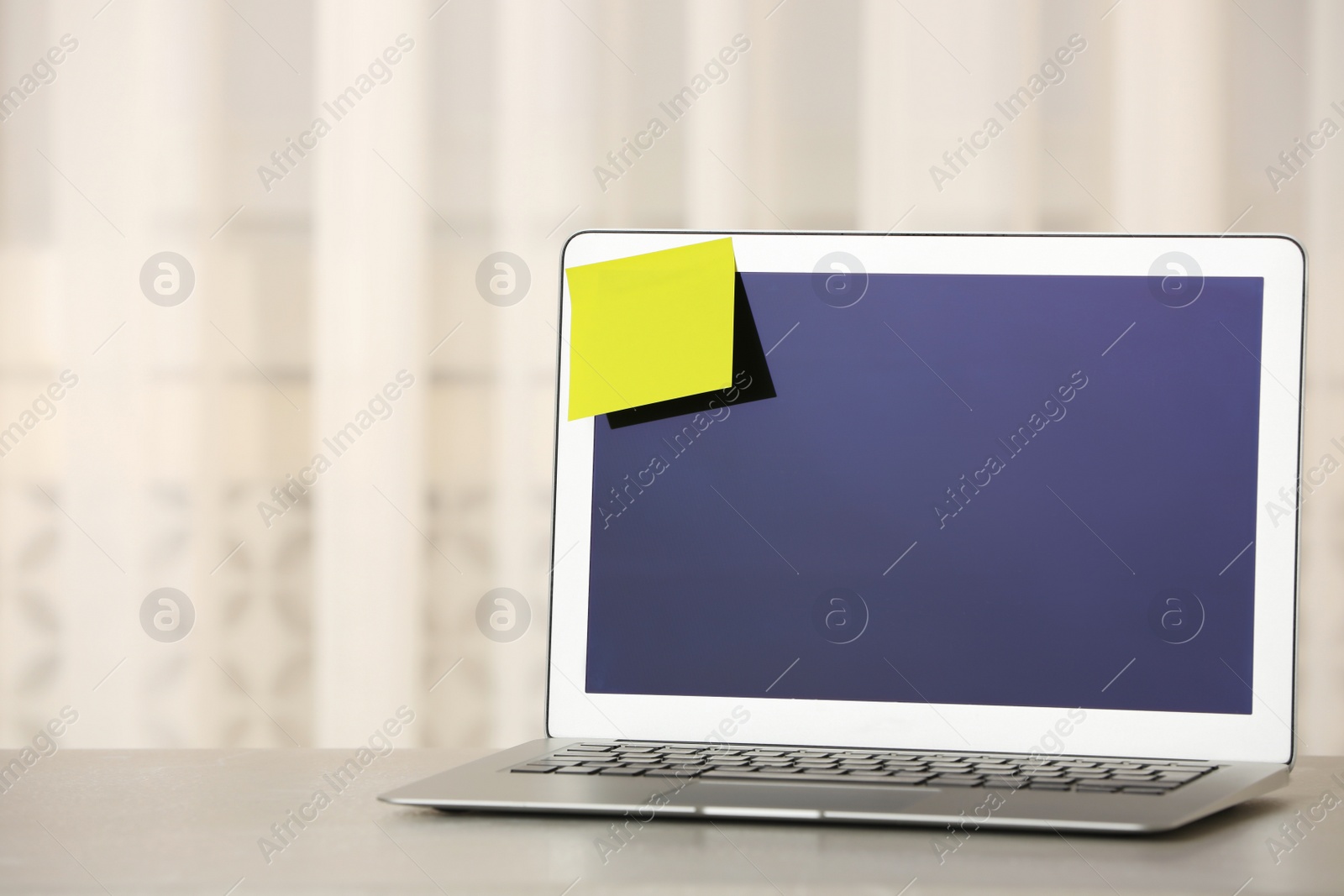 Photo of Laptop with empty sticky note on table indoors. Space for text