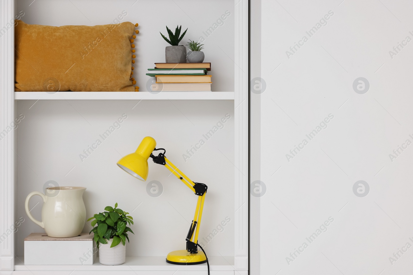 Photo of Shelves with lamp, books and different decor indoors, space for text. Interior design