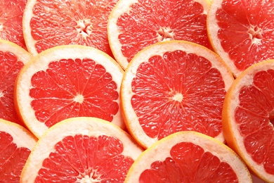 Many sliced fresh grapefruits as background, top view