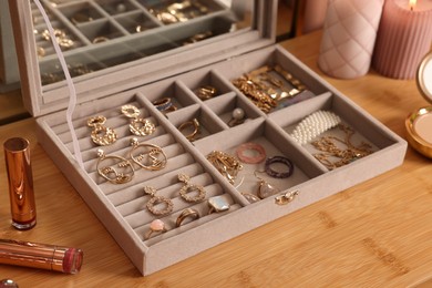 Elegant jewelry box with beautiful bijouterie and makeup products on wooden table