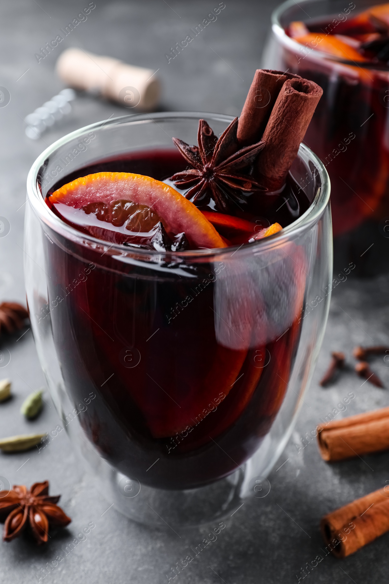 Photo of Aromatic mulled wine on grey table, closeup