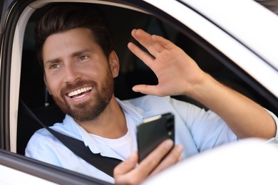 Photo of Happy bearded man using smartphone in car, view from outside