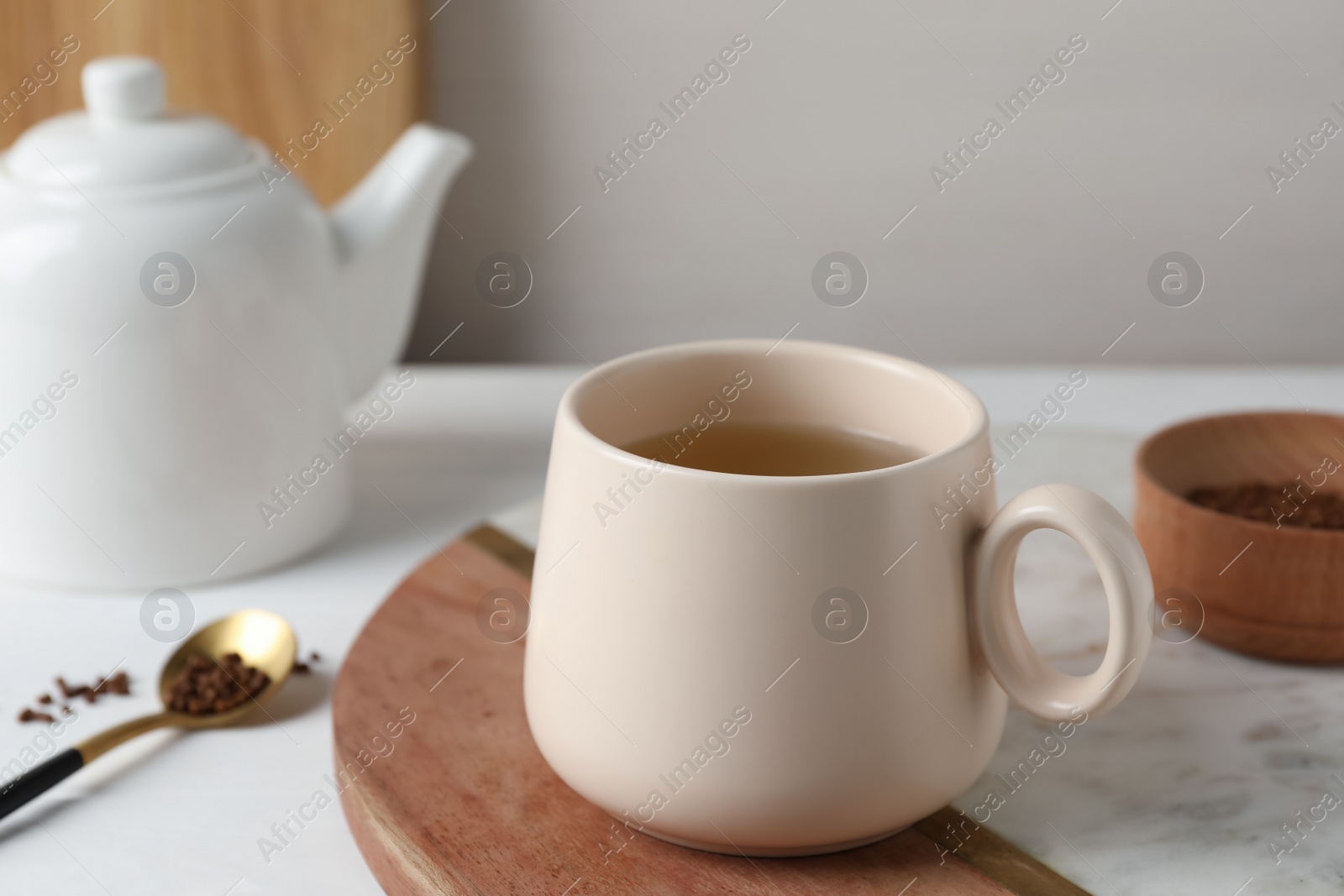 Photo of Cup of aromatic buckwheat tea and granules on white table