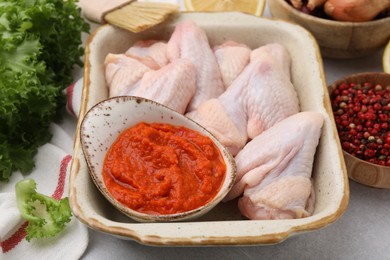 Fresh marinade, raw chicken and other products on light table, closeup