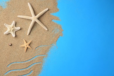 Photo of Beautiful starfishes and sand on blue background, flat lay. Space for text