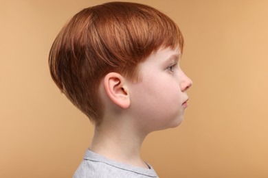 Hearing problem. Little boy on pale brown background