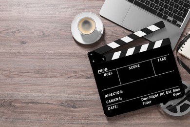Photo of Flat lay composition with movie clapper and film reel on wooden table, space for text
