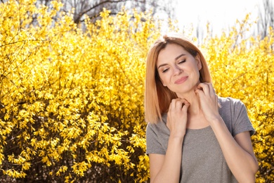 Woman suffering from seasonal allergy outdoors, space for text