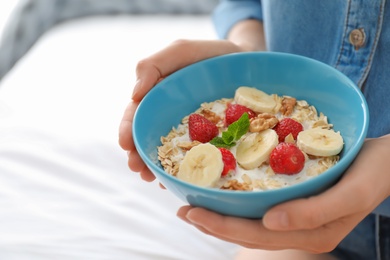 Photo of Woman holding bowl with delicious oatmeal and fruits, closeup. Healthy diet