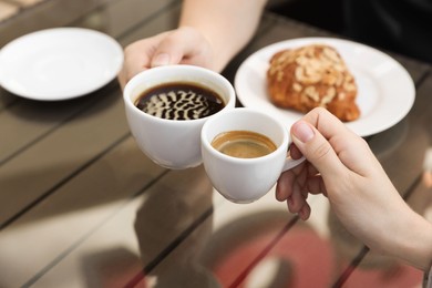 Photo of Man and woman drinking coffee at wooden table in outdoor cafe, closeup