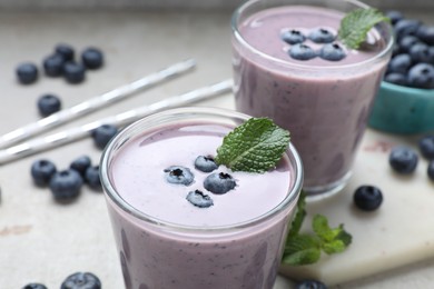 Photo of Freshly made blueberry smoothie on light grey table, closeup