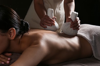 Young woman receiving herbal bag massage in spa salon, closeup