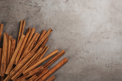 Aromatic cinnamon sticks on grey stone table, flat lay. Space for text