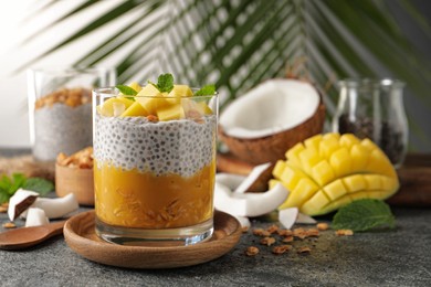 Photo of Delicious chia pudding with mango, mint and granola on grey table, space for text