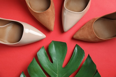 Photo of Flat lay composition with two pairs of beautiful shoes and monstera leaf on color background