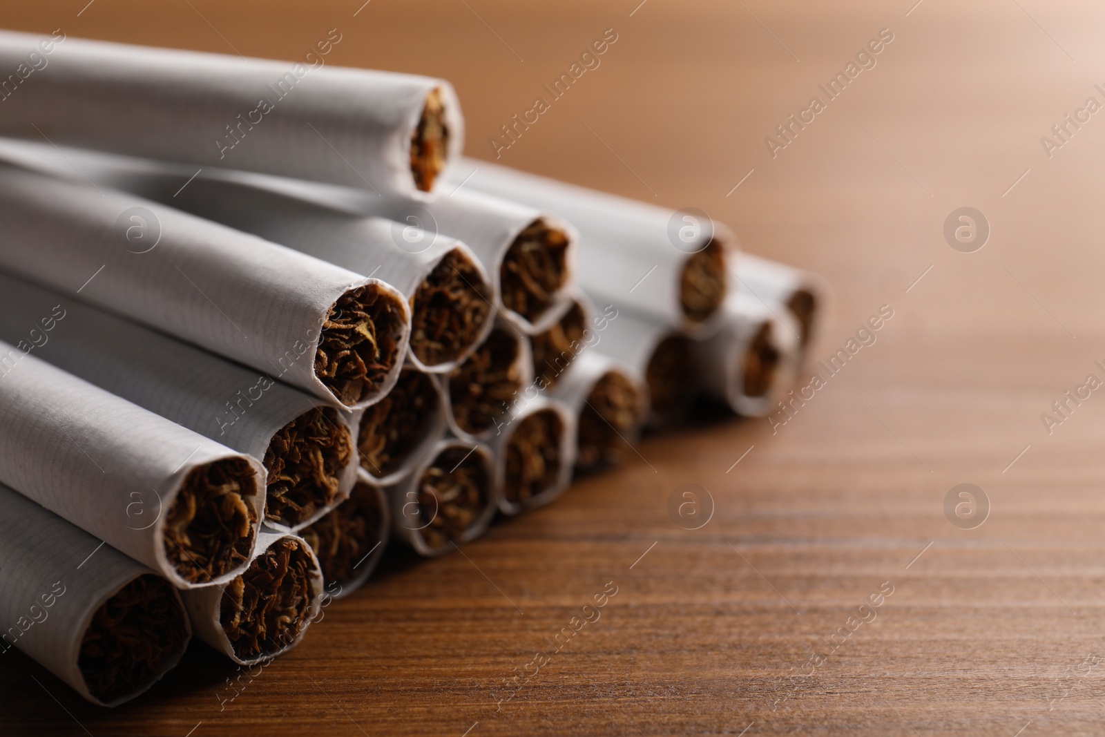 Photo of Pile of cigarettes on wooden table, closeup