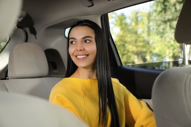 Beautiful young woman sitting in modern car