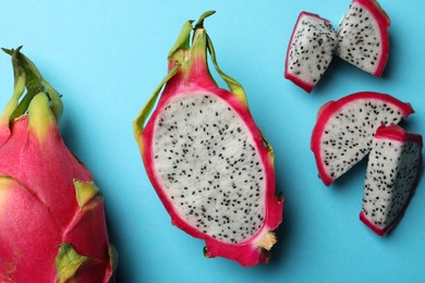 Photo of Delicious cut and whole white pitahaya fruits on light blue background, flat lay