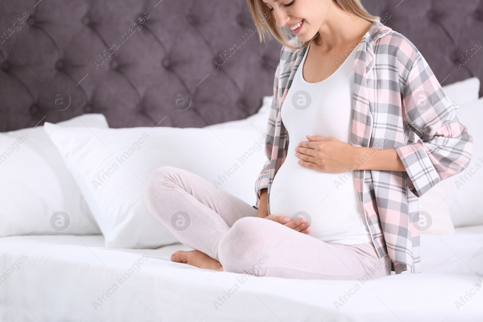 Photo of Happy pregnant woman sitting in bed at home, closeup