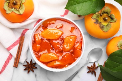 Bowl of tasty persimmon jam and ingredients on white marble table, flat lay