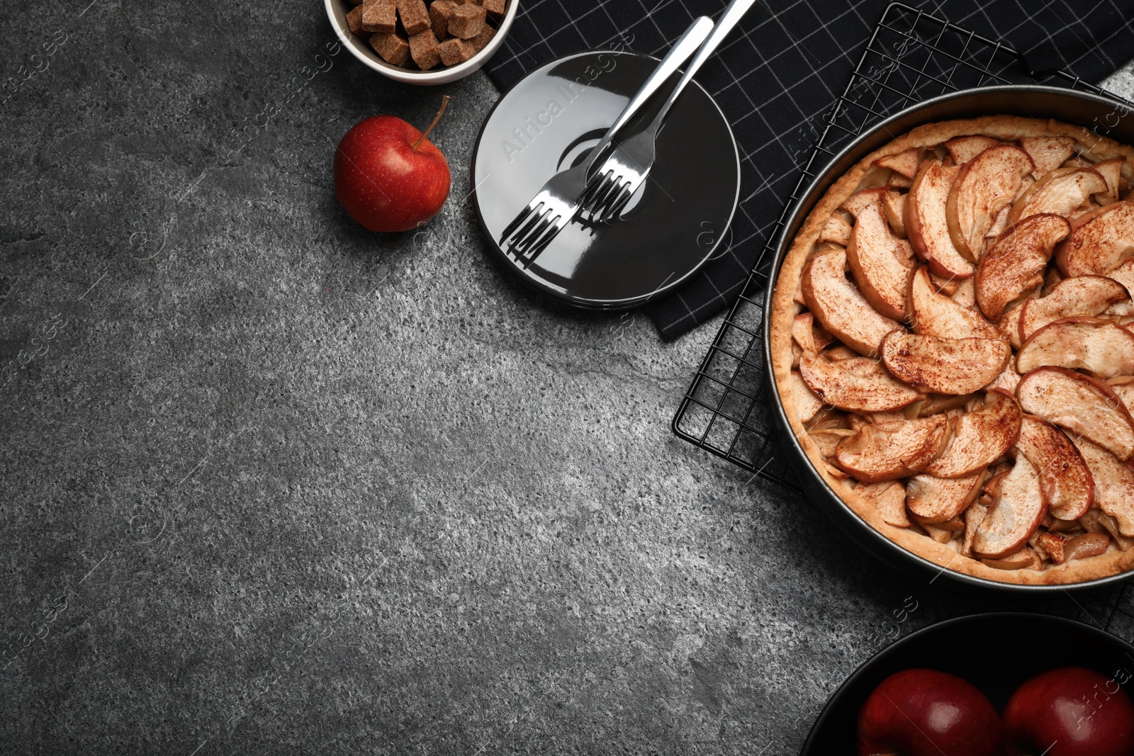 Photo of Delicious apple pie and ingredients on grey table, flat lay. Space for text