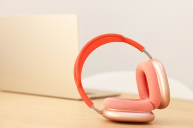 Photo of Modern headphones and laptop on wooden table