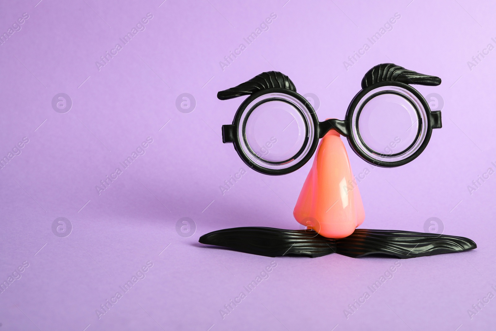 Photo of Funny face made with clown's accessories on violet background, space for text