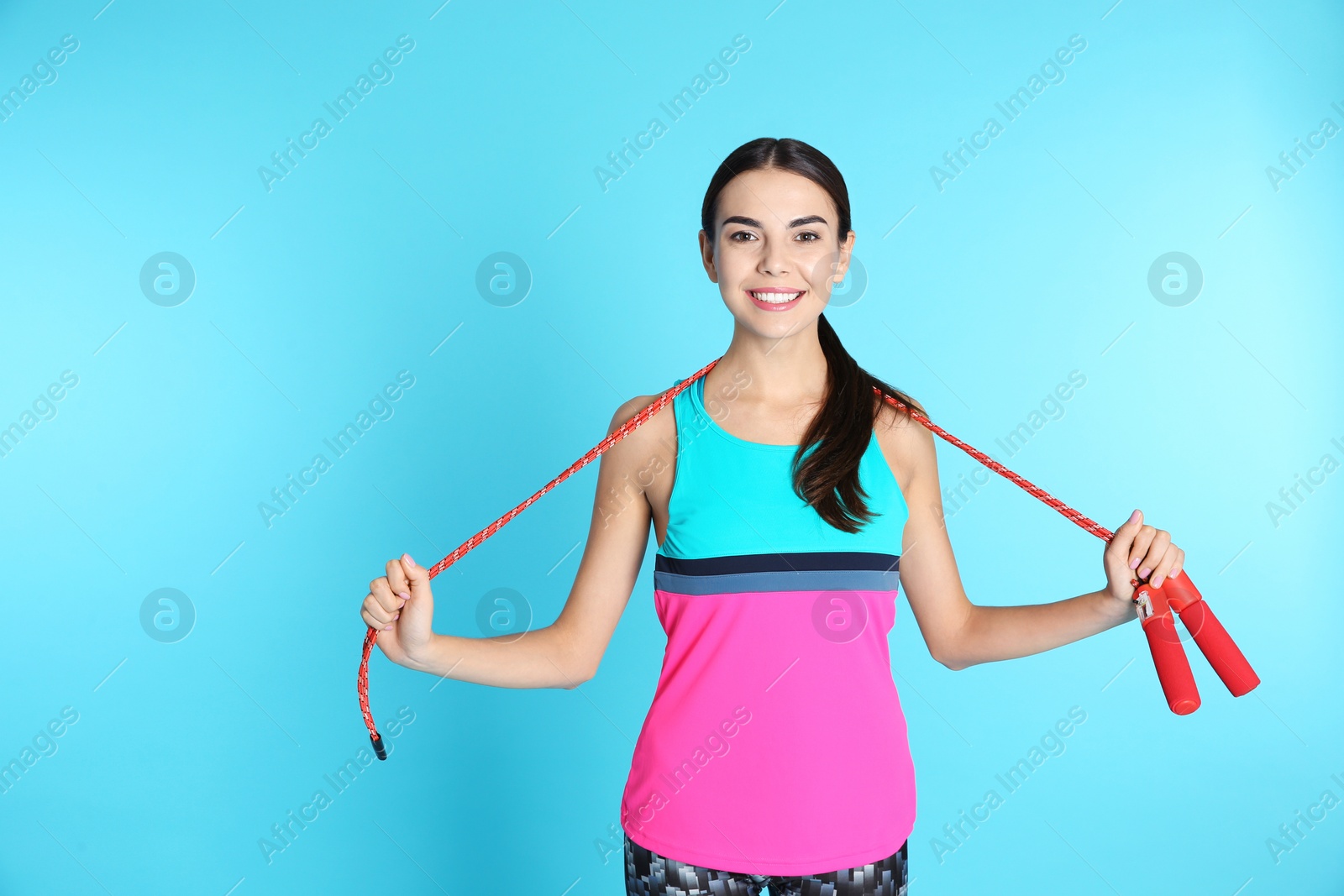 Photo of Portrait of young sportive woman with jump rope on color background