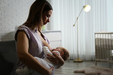 Photo of Young woman breast feeding her little baby at home. Space for text