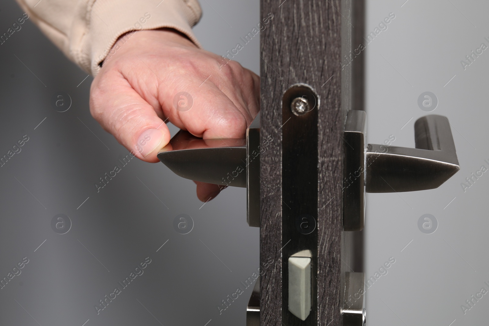Photo of Man opening wooden door indoors, closeup of hand on handle