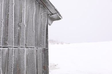 Wooden cottage covered with hoarfrost on snowy day. Space for text
